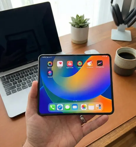 Un telefon pliabil Apple în mână, cu ecran colorat și aplicații deschise.