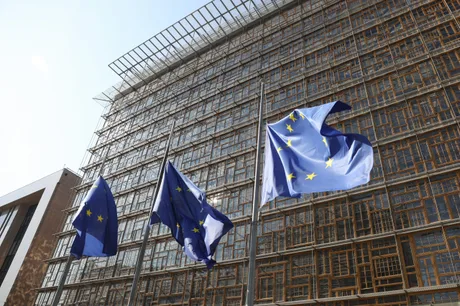 Clădirea Consiliului Uniunii Europene cu steagurile UE fluturând în față.