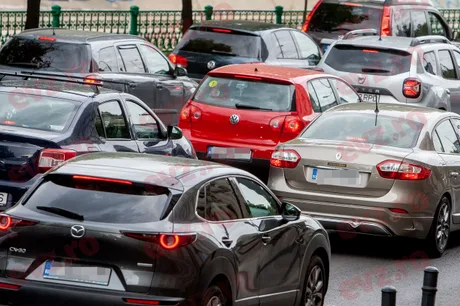 Trafic aglomerat în oraș, cu mașini diverse parcate pe stradă.