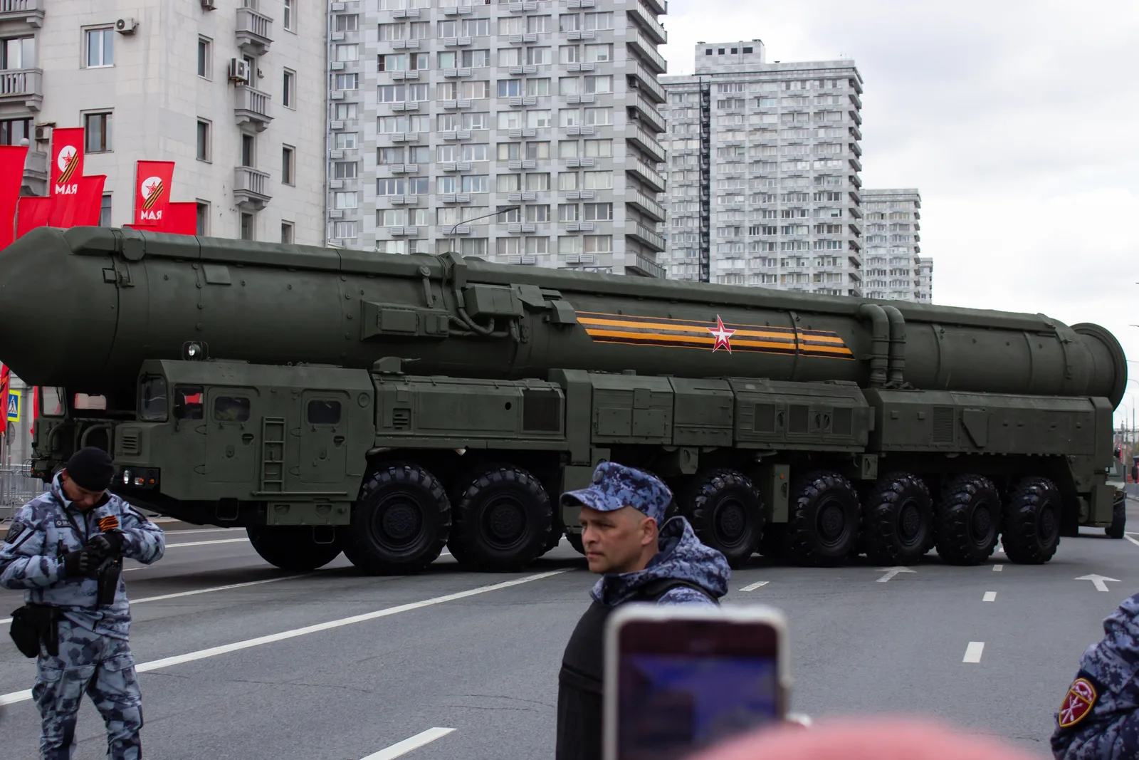 O rachetă militară pe o stradă dintr-un oraș, înconjurată de soldați.