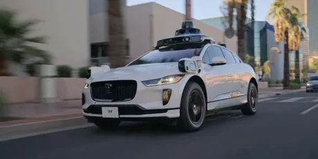 Vehicul autonom Waymo circulând pe o stradă din Phoenix, cu senzori pe acoperiș.