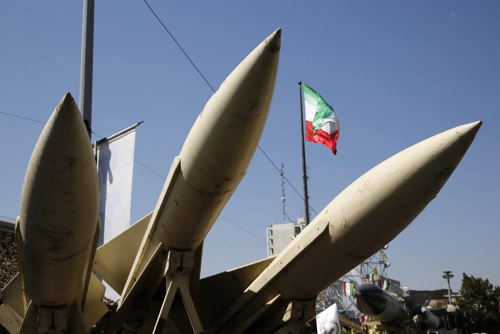 Rachete balistice expuse în Iran, cu steagul național în fundal.