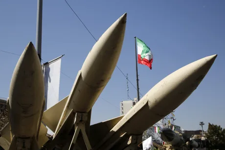 Rachete balistice expuse în Iran, cu steagul național în fundal.