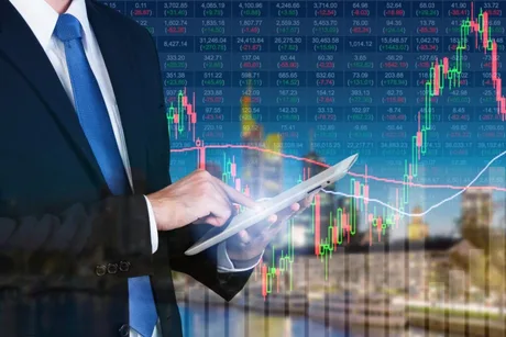 Un bărbat îmbrăcat la costum folosește o tabletă în fața unui grafic financiar.
