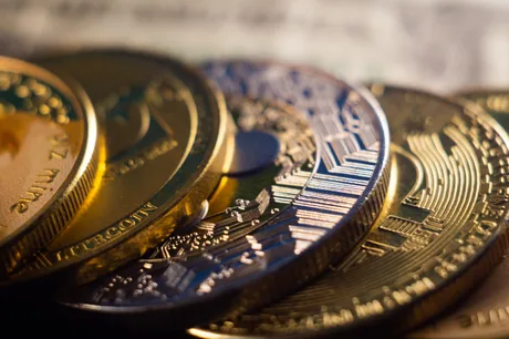 Monede Bitcoin așezate pe o suprafață, reflectând lumina.