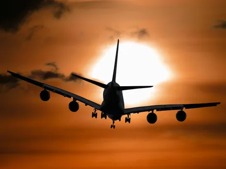 Avion în zbor pe fundalul unui apus dramatic.