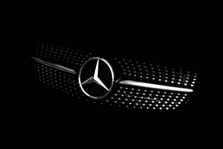 Logo-ul Mercedes pe fundal întunecat, simbol al industriei auto.
