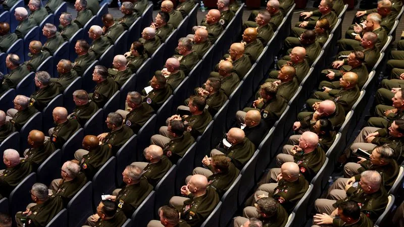 Militari așezați în rânduri, ascultând o prezentare oficială.