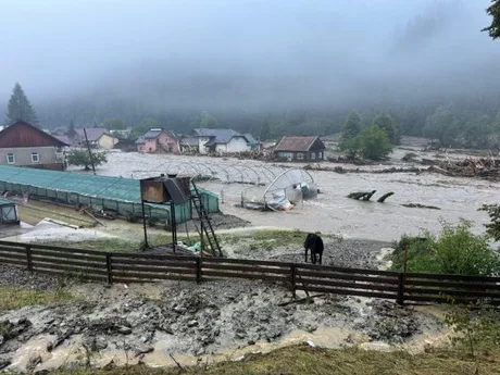 Peisaj afectat de inundații, case și terenuri inundate în zona rurală.