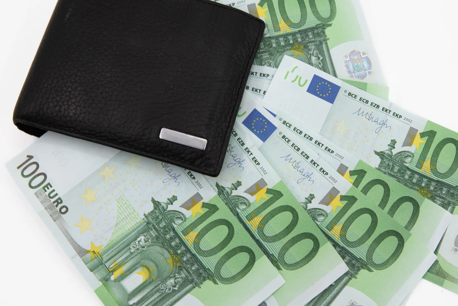Bancnote de euro și un portofel negru pe o masă.