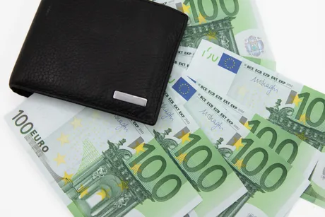 Bancnote de euro și un portofel negru pe o masă.