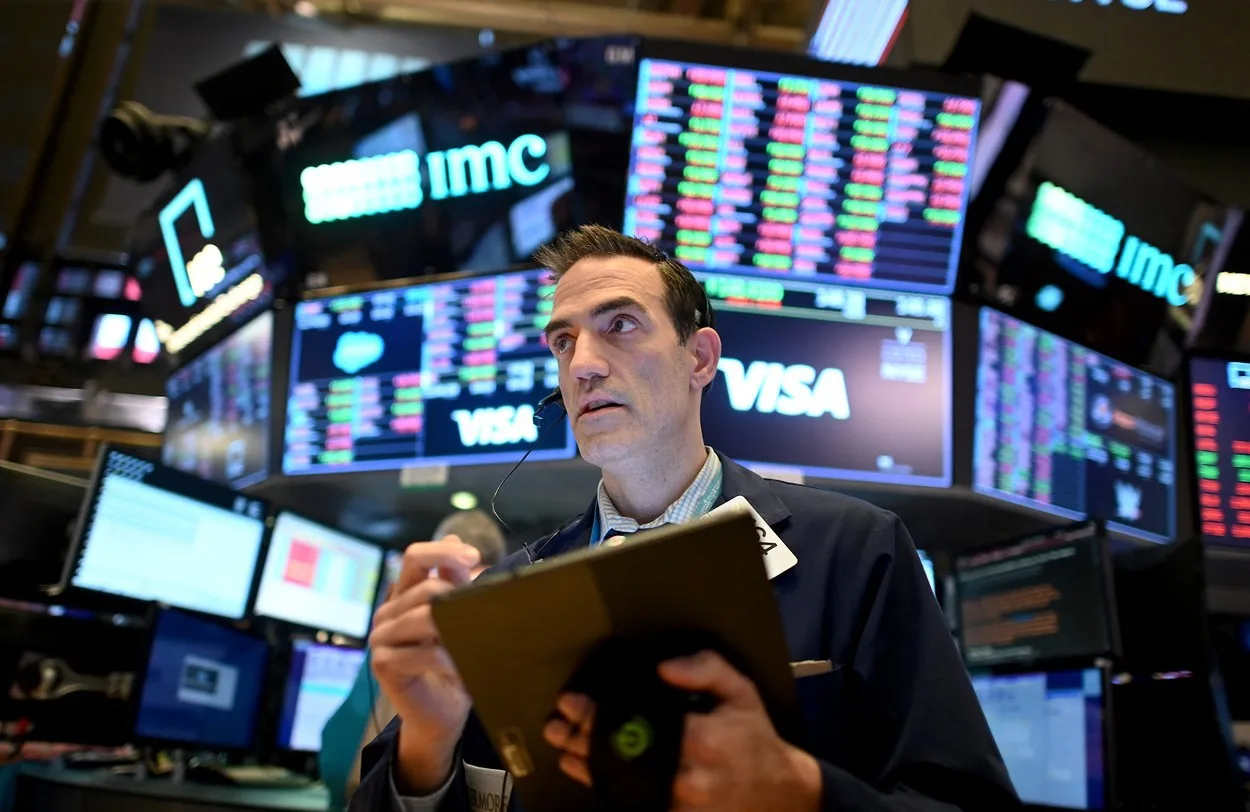 Un trader analizează date financiare pe ecrane multiple la bursă.