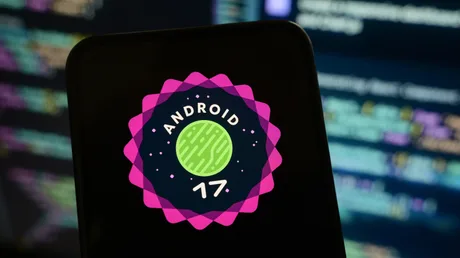 Logo Android 17 pe un telefon, înconjurat de coduri de programare.