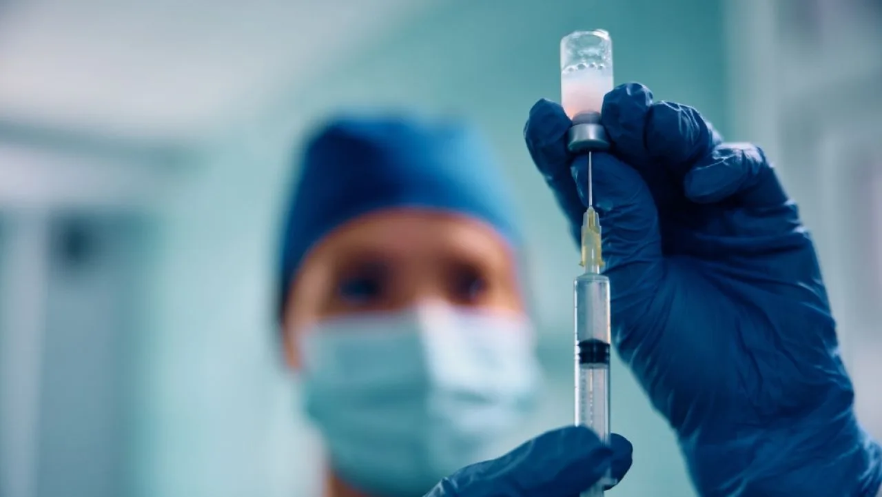 Un cercetător ține o seringă într-un mediu medical, pregătind un experiment inovator.