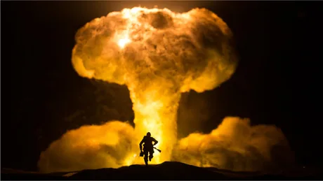 Explozie nucleară cu fum și flacără intensă în fundal.