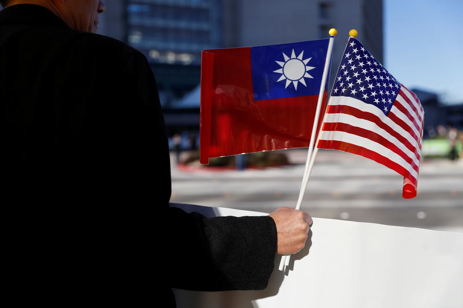 Un bărbat ține steagurile Taiwanului și SUA în timpul unui eveniment oficial.