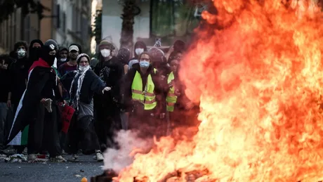 Protestatari în fața unei flăcări mari, în timpul revoltelor din Franța.