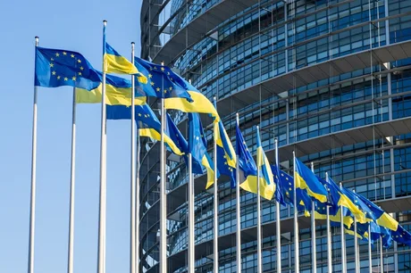 Steaguri ale Uniunii Europene și Ucrainei fluturând în fața unei clădiri moderne.