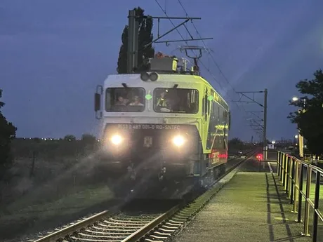 Locomotivă electrică pe calea ferată, în timpul nopții, iluminată de faruri.