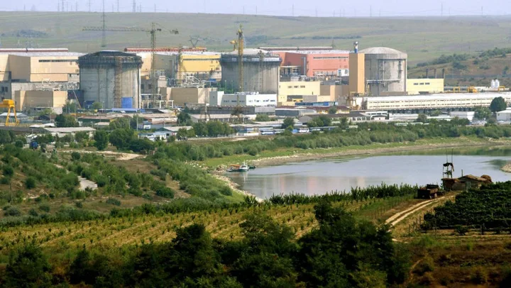 Centrala nucleară de la Cernavodă și Dunărea în fundal, peisaj rural.