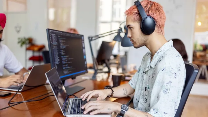 Tânăr lucrând la laptop, concentrat pe proiecte digitale, în birou modern.