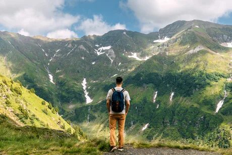Peisaj montan din România, cu un turist admirând natura.