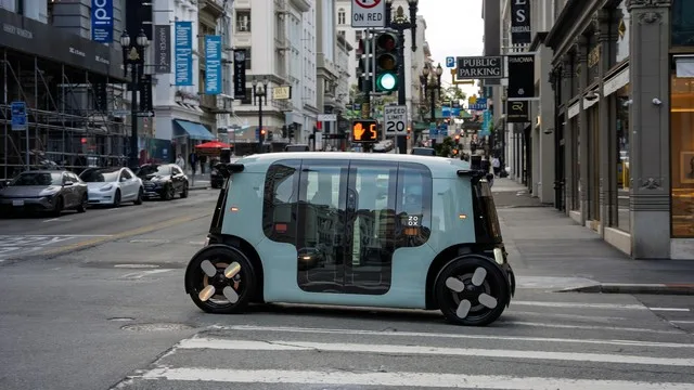 Robotaxi autonom Zoox în trafic, fără volan, pe o stradă urbană.