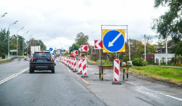 Drum în construcție cu semne de circulație și lucrări în desfășurare.