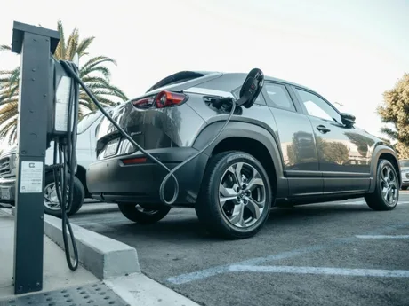 Mașină electrică conectată la o stație de încărcare într-o parcare.