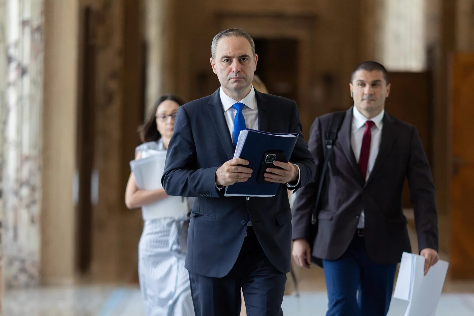 Ministrul Finanțelor discutând despre împrumuturi și dobânzi în cadrul unei întâlniri oficiale.