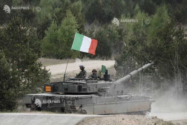 Tanc italian în mișcare, cu steagul Italiei fluturând pe fundalul pădurii.