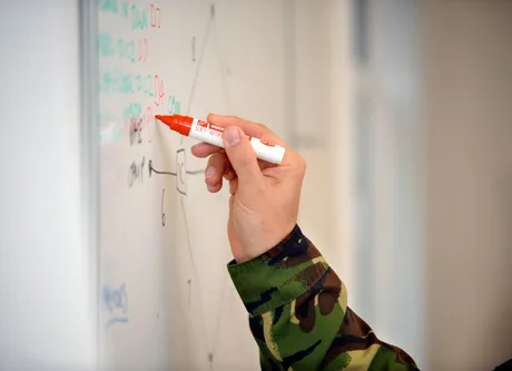 Un veteran scrie pe o tablă albă în uniformă militară.