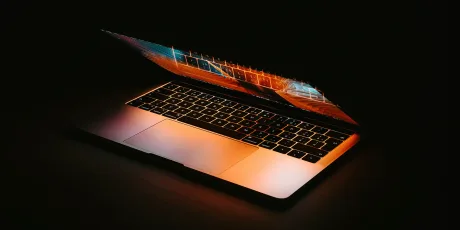 Laptop deschis cu un ecran luminos, evidențiind detalii tehnologice avansate.