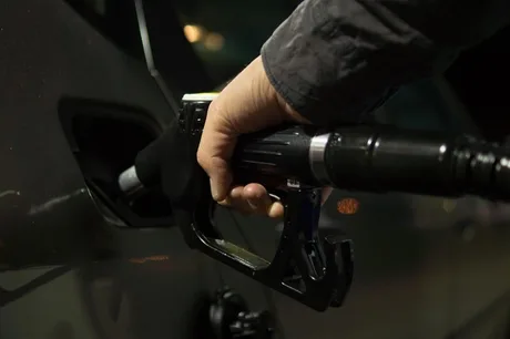 Persoană alimentând un vehicul cu motorină la o stație de benzină.