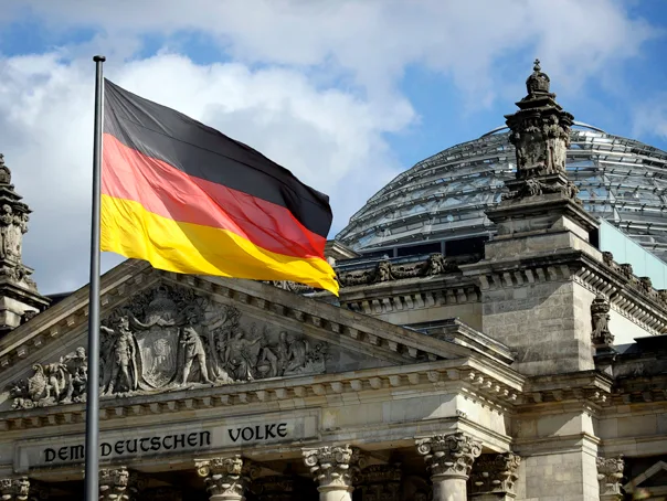 Steag german fluturând în fața unei clădiri guvernamentale emblematică.