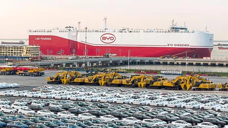 Parcare cu automobile BYD și un vapor de transport maritim în fundal.