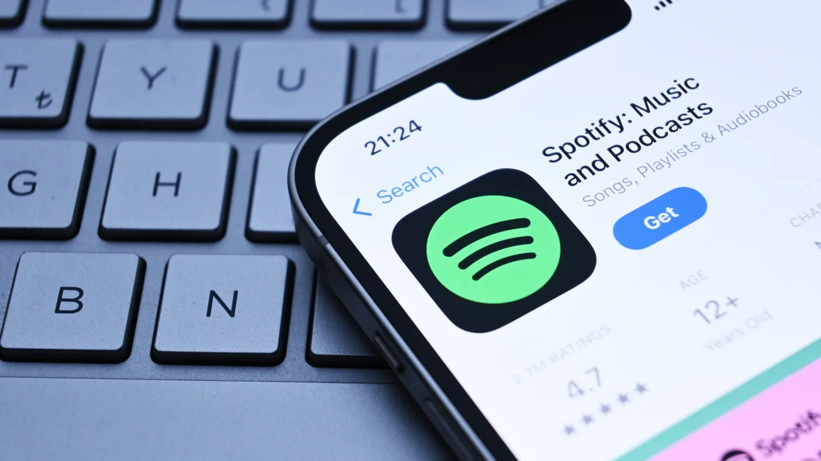Logo-ul Spotify pe un ecran de telefon mobil, lângă un tastat.