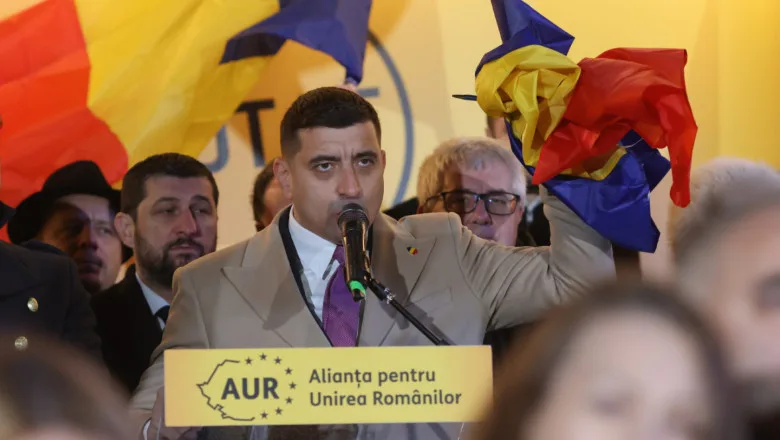 Un politician susține o inițiativă în fața mulțimii, cu steaguri românești în jur.