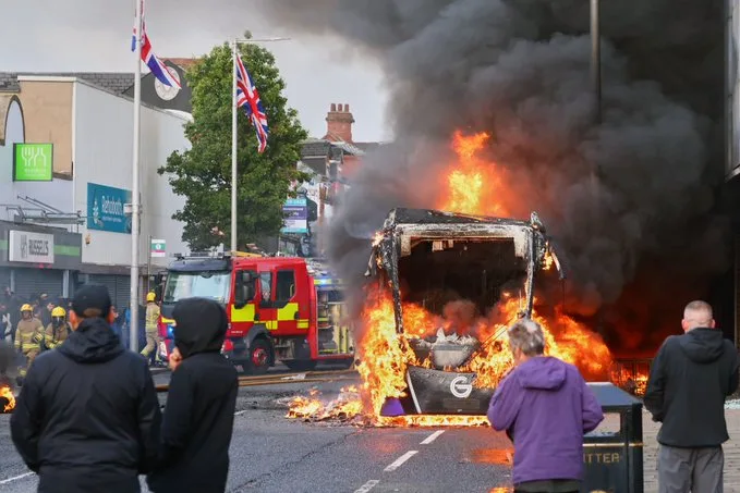 Huligani mascați incendiază un autobuz în Belfast, provocând haos și violențe.