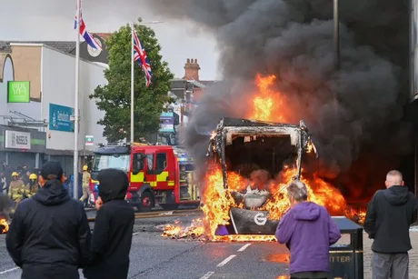 Huligani mascați incendiază un autobuz în Belfast, provocând haos și violențe.