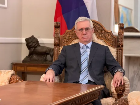 Diplomat rus în birou, cu steagul Rusiei în fundal.