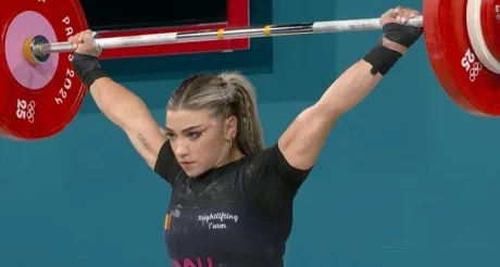 Sportivă în acțiune la competiția de haltere, demonstrând forță și tehnică.