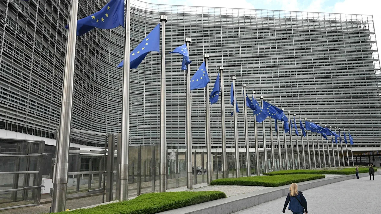 Clădirea Comisiei Europene cu steaguri fluturând în față.