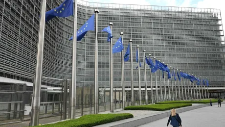 Clădirea Comisiei Europene cu steaguri fluturând în față.