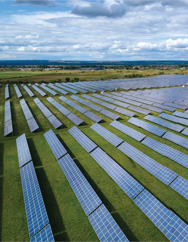 Parc fotovoltaic cu panouri solare pe un teren verde vast.