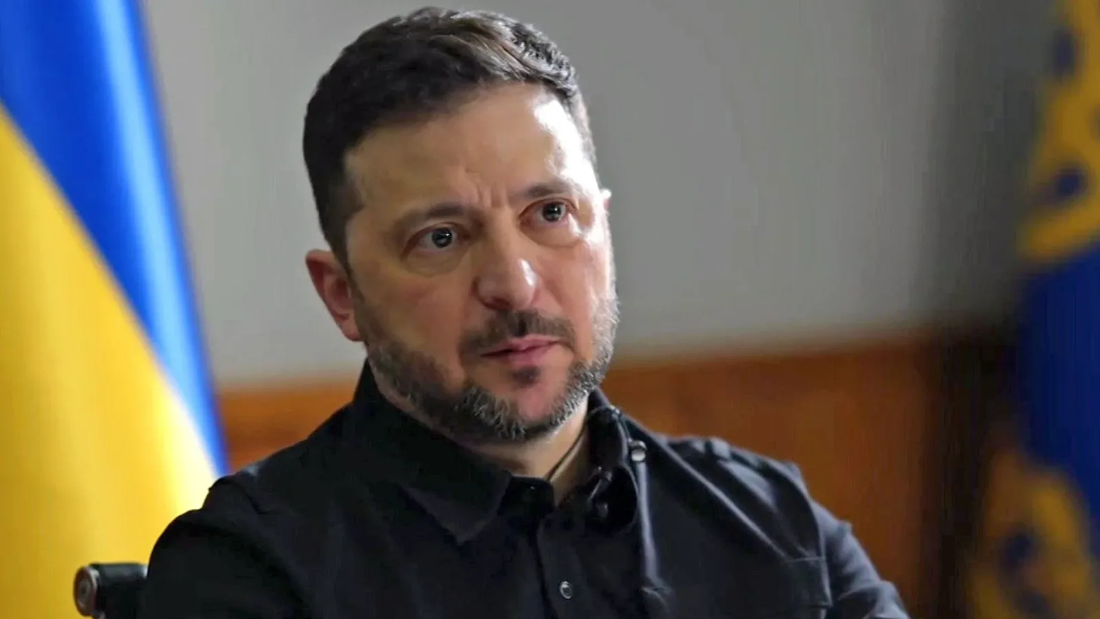 Zelenski discutând despre securitatea Ucrainei în fața drapelului național.