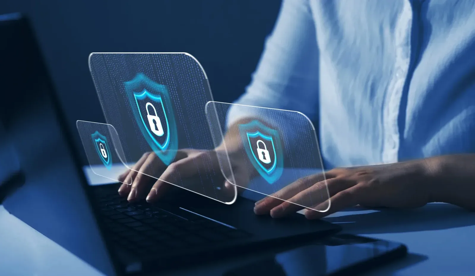 Persoană lucrând la un laptop cu simboluri de securitate digitală.