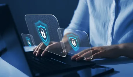 Persoană lucrând la un laptop cu simboluri de securitate digitală.