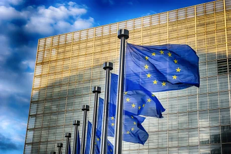 Steagurile Uniunii Europene fluturând în fața unei clădiri moderne.