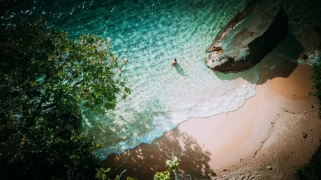 Plajă exotică cu ape cristaline și stânci, ideală pentru vacanțe.
